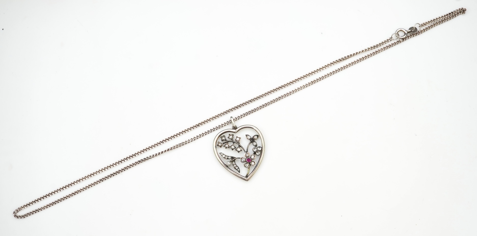 A diamond pendant, designed as a spray of flowers in a heart-shaped frame, set with rose-cut diamonds and a circular-cut ruby, to a later silver chain, pendant 3.1cm, chain length 44cm